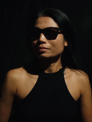 Directed portrait lit from the front against a black ground, shoulders squared to the camera
