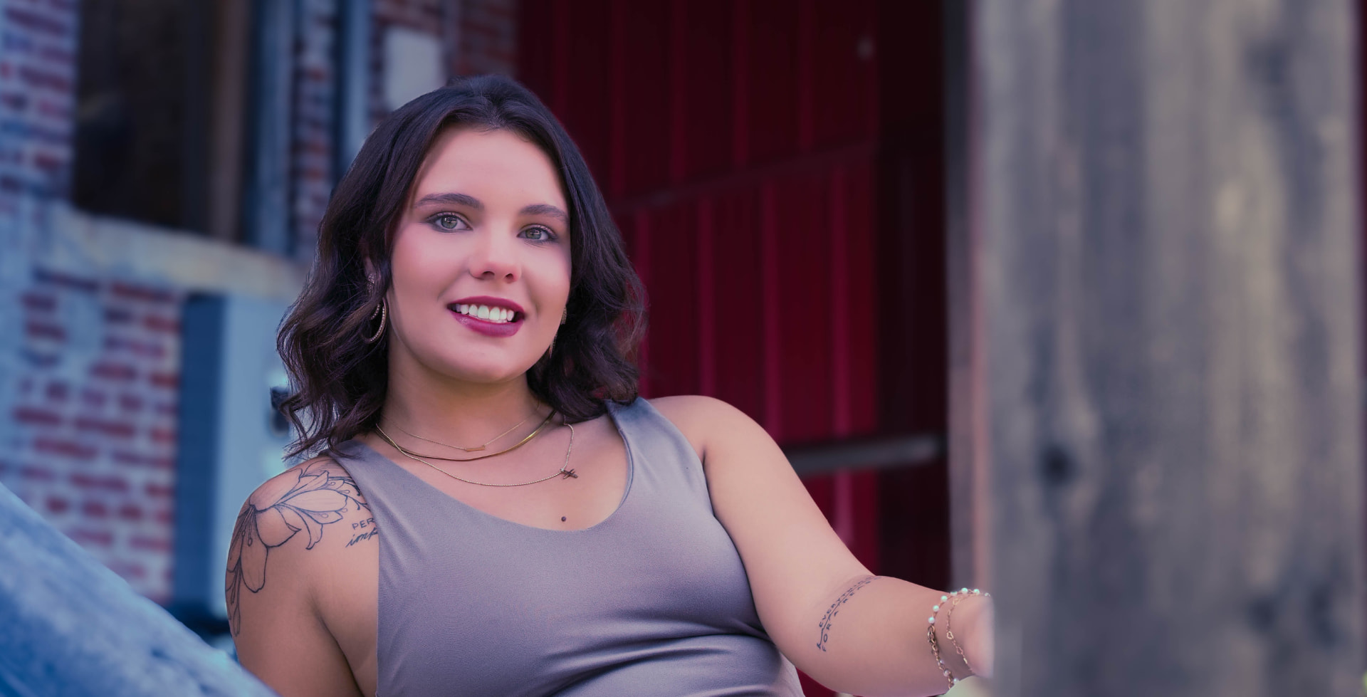 Emily smiling in golden light against a red door in the Kansas City West Bottoms