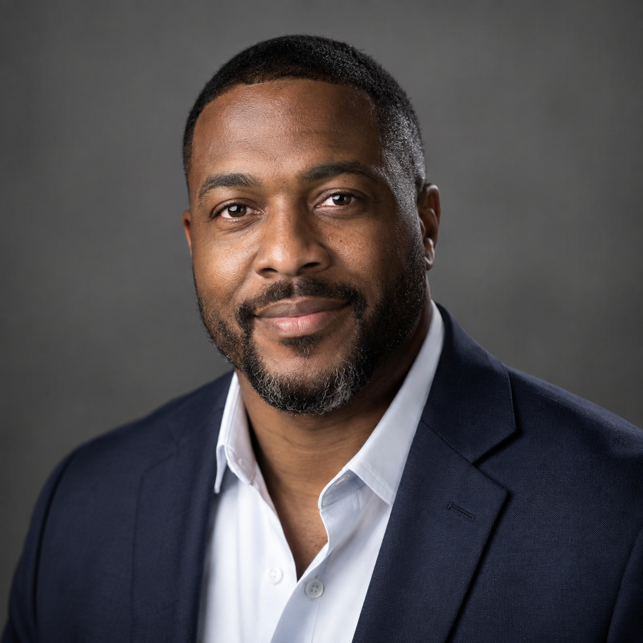 Directed professional headshot of a man in a navy blazer, light shaped across one side of the face, photographed on location in Kansas City